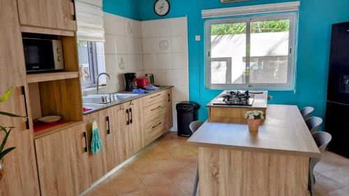 a kitchen with blue walls and a sink and a counter at Maison des Sables - Turquoise in Port Louis