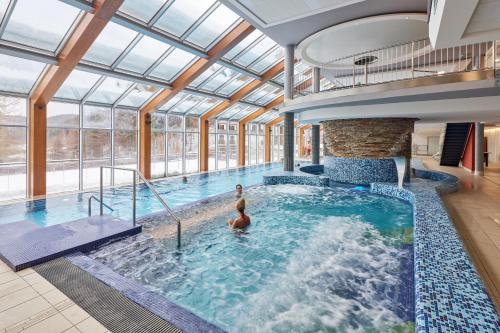 a large indoor pool with two people in it at Wellness hotel Horal, Velké Karlovice in Velké Karlovice