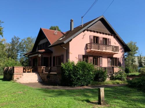 Cette maison rose dispose d'une terrasse couverte et d'un balcon. dans l'établissement Charmante Demeure Piscine au Calme Parc Tennis, à La Walck