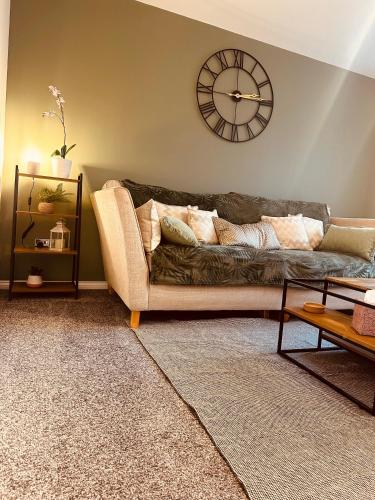 a living room with a couch and a clock on the wall at Regent Apartment - FREE PARKING in Blythe