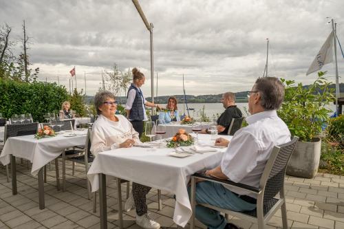 a group of people sitting at tables at a restaurant at Seehotel Beinwil am See Swiss Quality in Beinwil