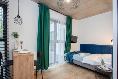 a bedroom with a bed with green curtains and a desk at Apartamenty Silver Place in Szczecin