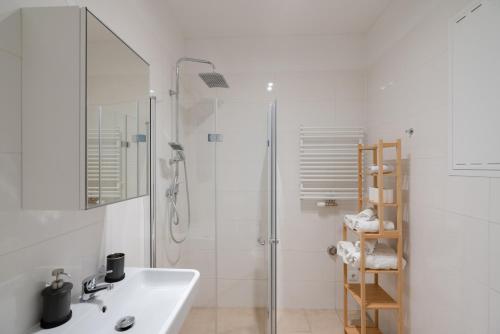 a white bathroom with a sink and a shower at New Favoriten - Serviced Apartments in Vienna