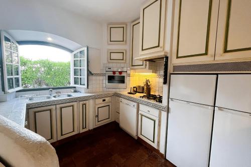 une cuisine avec des placards blancs et une grande fenêtre dans l'établissement Beautiful fisherman house and a mooring - WIFI, à Grimaud