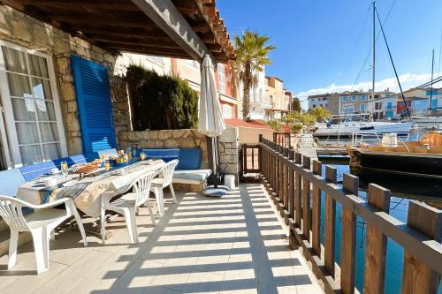 d'une terrasse avec une table, des chaises et un bateau. dans l'établissement Big fisherman house with WIFI and a mooring close to the beach, à Grimaud
