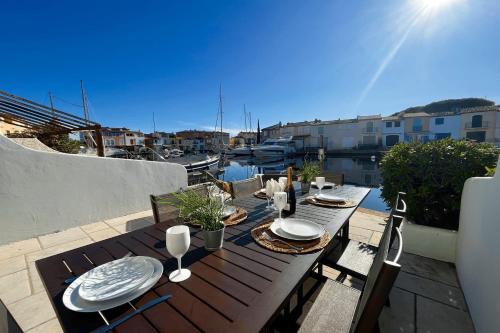 une table en bois avec des assiettes et des verres sur un balcon dans l'établissement Renovated fisherman house next to the beach - AC WIFI mooring, à Grimaud