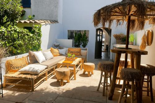 une terrasse avec un canapé, une table et des tabourets dans l'établissement Renovated fisherman house next to the beach - AC WIFI mooring, à Grimaud