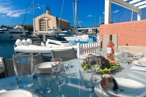 une table avec des verres et une assiette de nourriture dans un port de plaisance dans l'établissement Fisherman house with WIFI AC and a 14m-mooring, à Grimaud