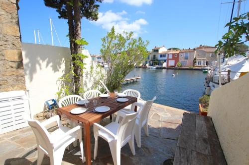 - une table et des chaises en bois sur une terrasse au bord de l'eau dans l'établissement Fisherman house close to the beach - WIFI, à Grimaud