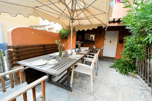 - une table en bois avec des chaises et un parasol sur la terrasse dans l'établissement Fisherman house with WIFI AC and a 14m-mooring, à Grimaud