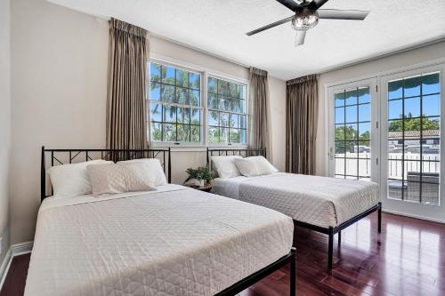 two beds in a bedroom with windows and a ceiling fan at Spacious Luxury Villa in Hollywood 6BR 5-Bath 5-Min Walk to Beach & Attractions in Hollywood