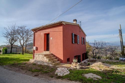 a small red brick house with stairs in a field at Il Capriccio del Papa in Genga