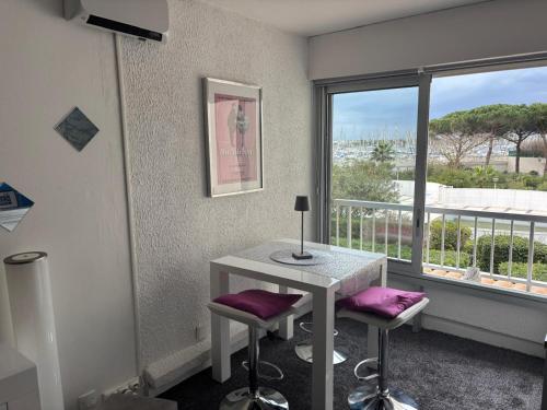 une pièce avec une table et deux tabourets et une fenêtre dans l'établissement Cosy Studio Port Cap d'Agde, au Cap d'Agde