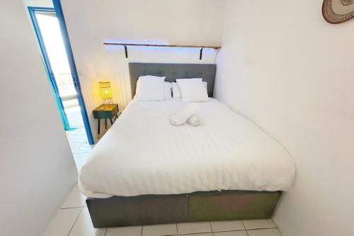 une chambre avec un lit avec des draps blancs et des oreillers dans l'établissement Le Seaview-Quiet-Swimming pool-Car park-Seafront, à Cannes