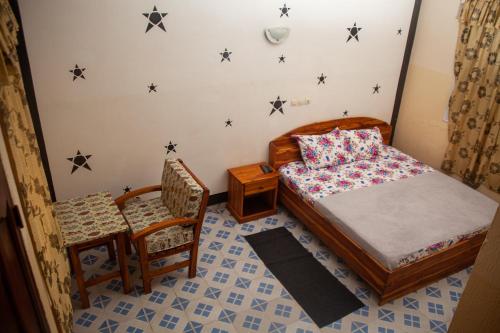 a bedroom with a bed and a chair with stars on the wall at Amy's Hotel in Lomé