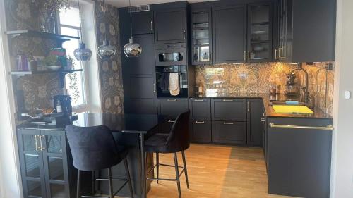a kitchen with black cabinets and a black table and chairs at Seaside city appartment in Tromsø