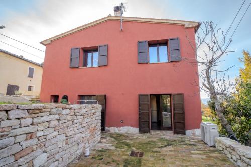 a red house with a stone wall at Il Capriccio del Papa in Genga