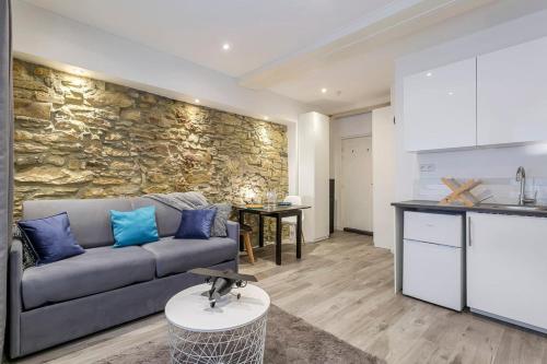 un salon avec un canapé et un mur en pierre dans l'établissement Hamac Suites - Studio Port du Temple - 2 people, à Lyon