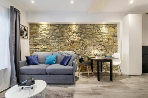 un salon avec un canapé et un mur en pierre dans l'établissement Hamac Suites - Studio Port du Temple - 2 people, à Lyon