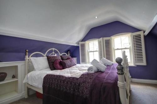 a bedroom with a bed with purple walls and windows at The Little Angel Cottage in Whitby