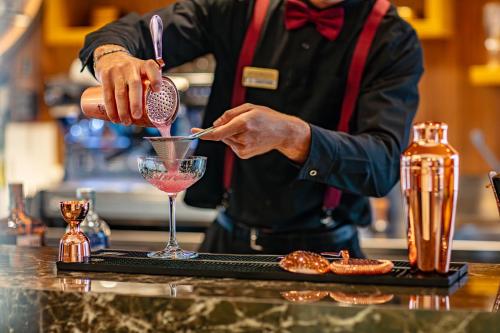 a man is making a drink in a martini glass at Hotel Argentina in Grado