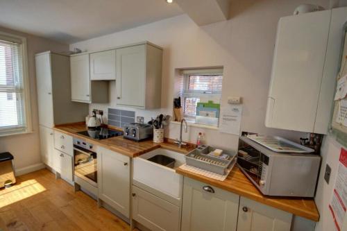 a kitchen with white cabinets and a wooden counter top at The Little Angel Cottage in Whitby