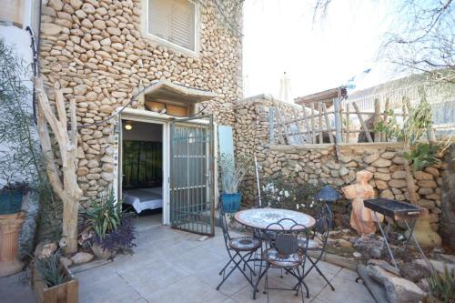 a patio with a table and chairs and a stone wall at Beatrice Hospitality in Neve Zohar