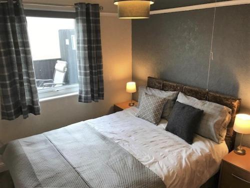 een slaapkamer met een bed met kussens en een raam bij 3 Bedroom Detached Holiday Chalet SouthShore Park in Bridlington
