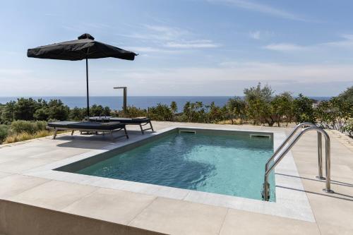 a swimming pool with a table and an umbrella at Fari Stone Villas in Skala Marion