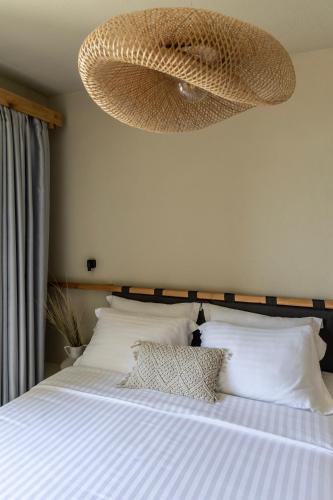 a bedroom with a bed with white sheets and a chandelier at Fari Stone Villas in Skala Marion