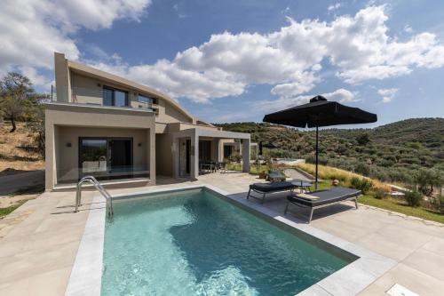 a house with a swimming pool and an umbrella at Fari Stone Villas in Skala Marion