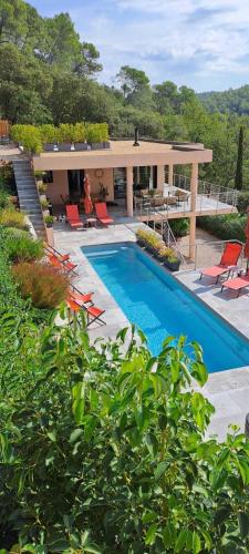a swimming pool with chairs and a house at Les Hauts du Peireguier in La Motte