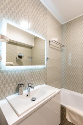 a bathroom with a sink and a mirror and a tub at Sunset Resort 109 in Fonyód