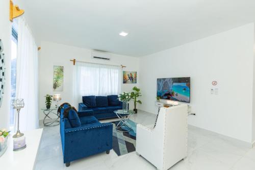 a living room with a blue couch and a tv at Crown ll-3 Bedrooms-Pool-Close to everything! in San Felipe de Puerto Plata