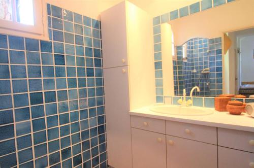 La salle de bains est pourvue de carrelage bleu, d'un lavabo et d'un miroir. dans l'établissement Villa Sanderling - A 3 km de St-Tropez - Villa climatisée avec piscine privée, à Saint-Tropez