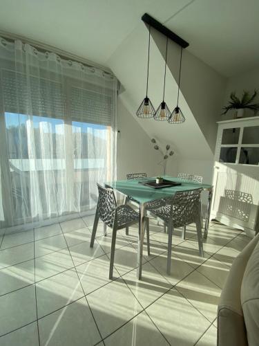 a dining room with a green table and chairs at Les terrasses des myosotis in Blotzheim