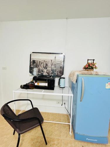 a chair sitting next to a desk with a refrigerator at DS Self service Apartment 02 in Phuket