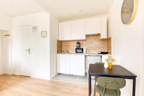 une cuisine avec des armoires blanches et une table et des chaises dans l'établissement Studio aux Porte de Paris, à Gentilly