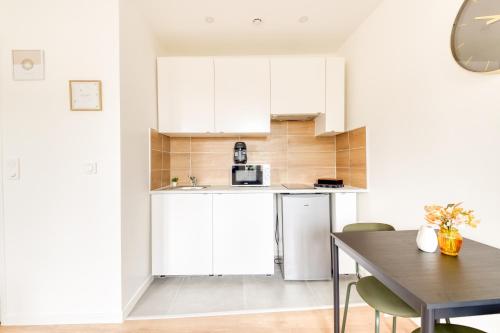 une cuisine avec des armoires blanches et une table avec des chaises dans l'établissement Studio aux Porte de Paris, à Gentilly