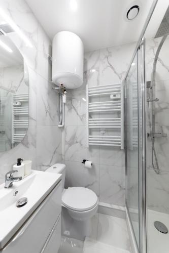 une salle de bain blanche avec toilettes et douche dans l'établissement Studio aux Porte de Paris, à Gentilly