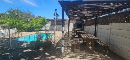 a swimming pool with benches next to a building at Kelkiewyn Guesthouse Caledon in Caledon