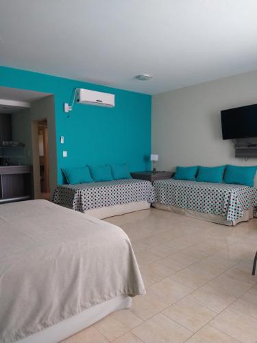a bedroom with two beds and a blue wall at Costa del Faro Apart Hotel in Balneario El Condor