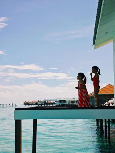 two girls standing on a dock near the water at Bubblefish Water Villa in Kampong Bum Bum