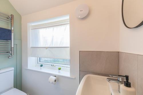Un baño con lavabo, inodoro y ventana. en Charming 5-Bed Home with Garden and Parking, en Winchester
