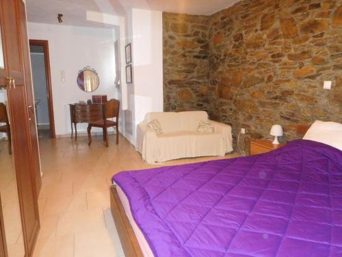 a bedroom with a purple bed and a stone wall at Saronic Citadel Seaside villa in Salamís