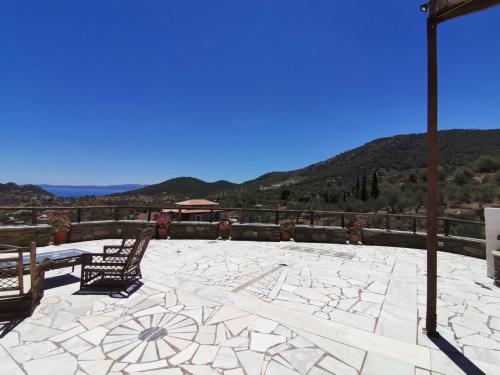 a patio with a table and chairs and mountains at Saronic Citadel Seaside villa in Salamís