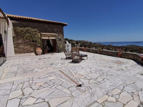 a stone patio with two chairs and a building at Saronic Citadel Seaside villa in Salamís