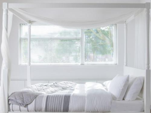 a white bedroom with a bed and a window at Cosy Garden Flat, Private Hot Tub & Four Poster Bed in York