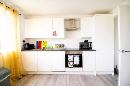 a kitchen with white cabinets and a microwave at 18CB 2 bedroom Apartment, Sleeps 4, Long Stays, Free Parking in a great location in Swindon