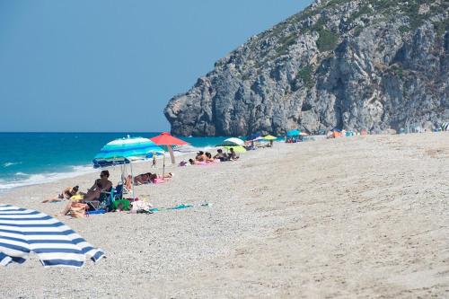 a group of people sitting on a beach with umbrellas at Blue Dream Seaside Villa with superb sea views in Kymi